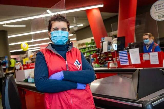 在法国巴黎一家超市，收银员戴着口罩和手套工作