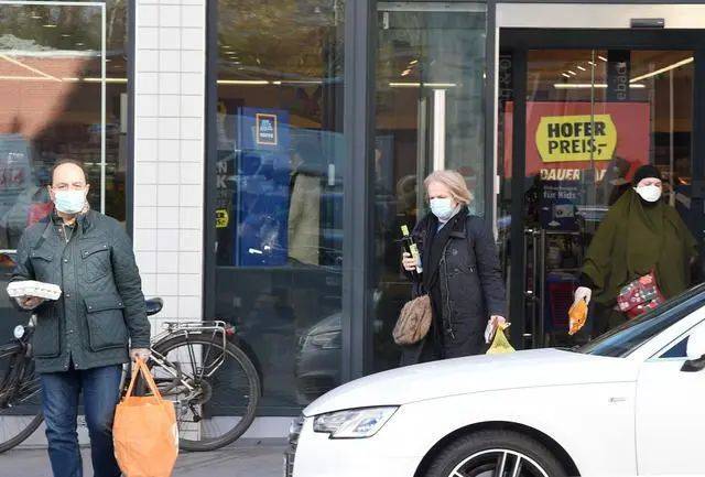  4月1日，在奥地利维也纳，佩戴口罩的人们走出超市。