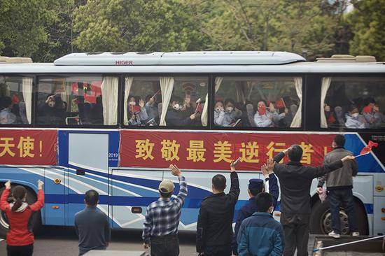武汉市民在医疗队的车辆外挥手道别。
