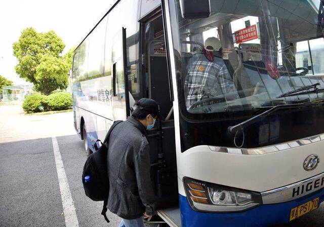 旅客佩戴口罩登上长途客车。