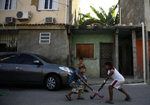 2016年里约奥运会期间，里约曼盖拉贫民窟，几名孩子在狭窄的街道上打曲棍球。新华社记者王鹏摄