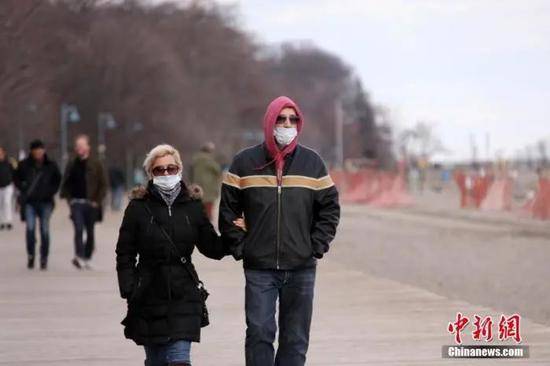 当地时间4月11日，复活节假期，加拿大多伦多市民佩戴口罩在湖滨公园散步踏青。中新社记者余瑞冬摄
