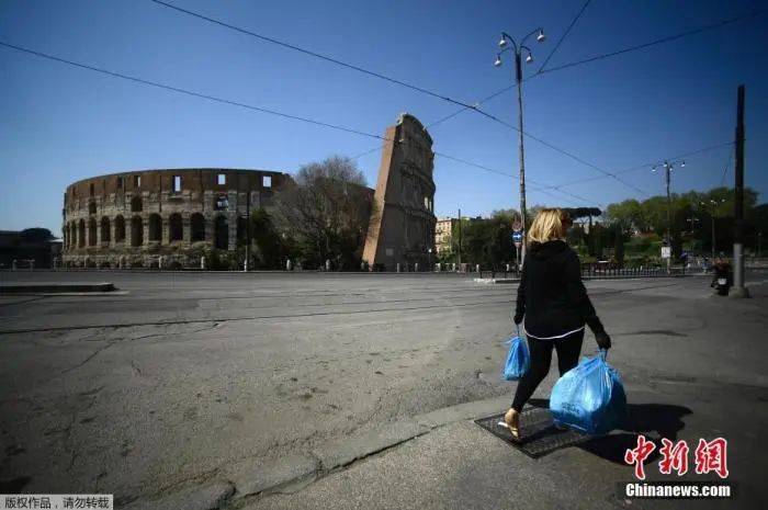 当地时间4月10日，一名妇女背着垃圾袋穿过罗马体育馆纪念碑附近。意总理孔特日前表示，原定4月13日结束的全国“封城”措施将延长到5月3日。