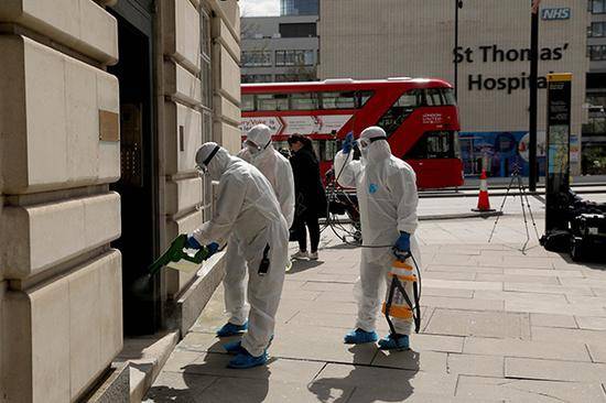 4月7日，在英国伦敦，工作人员为一座建筑消毒。新华社图