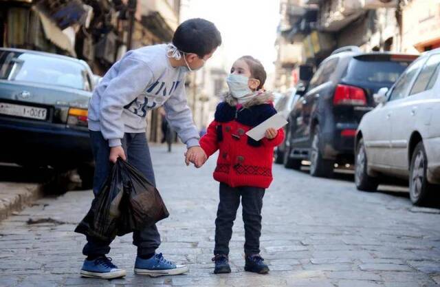  4月12日，在叙利亚大马士革，两名佩戴口罩的儿童走在街头。新华社发（阿马尔摄）