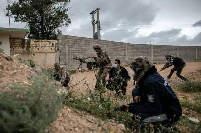  3月25日，在利比亚的黎波里，利比亚民族团结政府武装人员戴着口罩在战斗。新华社发（阿姆鲁摄）