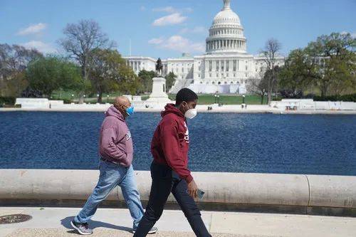 4月11日，在美国首都华盛顿，两名男子戴着口罩从国会大厦附近走过。新华社记者刘杰摄