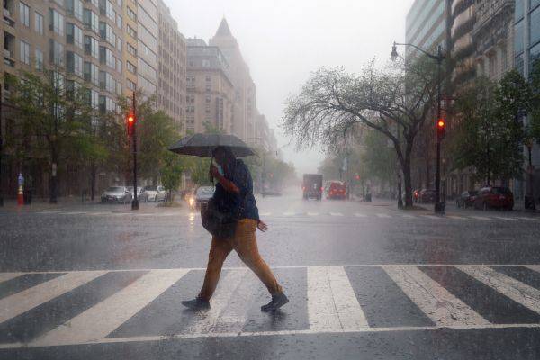  4月13日，在美国首都华盛顿，一名戴着口罩的男子在雨中过马路。新华社