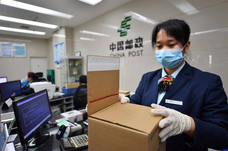 东四邮政支局，邮政工作人员在使用免胶带的易封箱包装邮递物品。摄新京报记者李木易