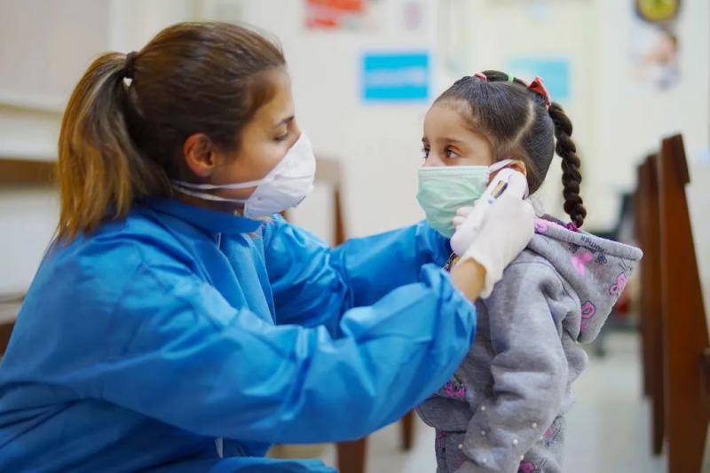 儿基会图片|黎巴嫩贝鲁特一家初级卫生保健中心，护士在疫情期间为一名女孩测量体温