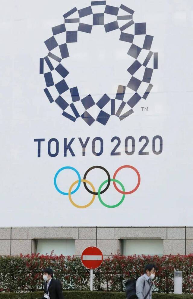 ▲3月25日，戴口罩的行人经过东京都厅前的东京奥运会会徽。（新华社记者杜潇逸摄）
