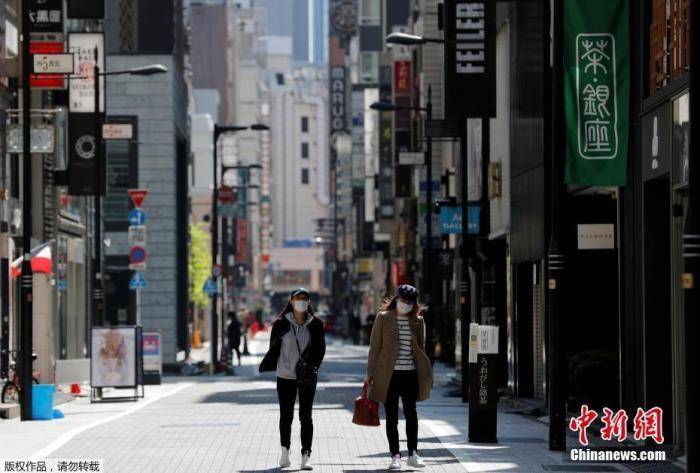当地时间4月25日，日本东京，戴口罩的女士走过空无一人的购物区。