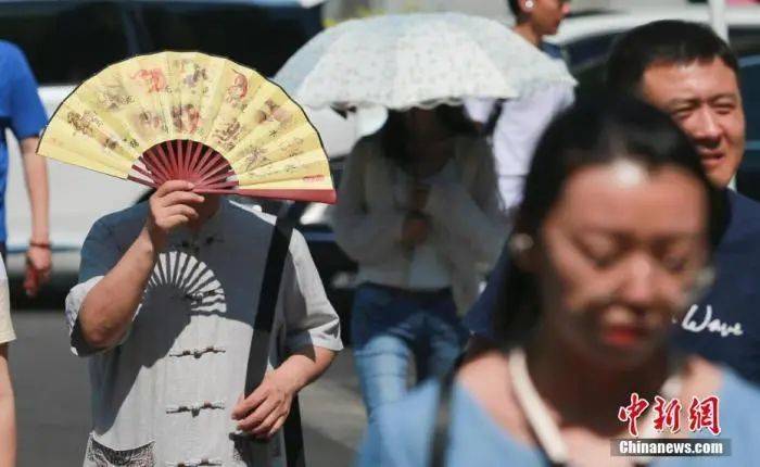 资料图：北京街头，民众遮阳出行。中新社记者贾天勇摄