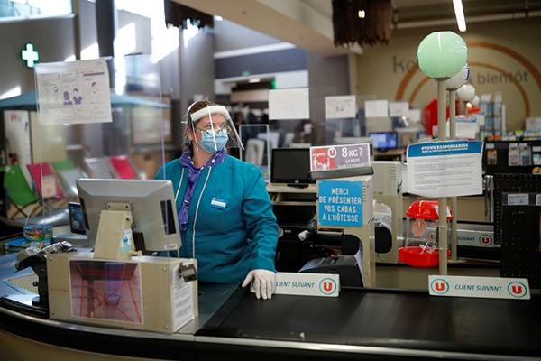在法国布列塔尼大区，一名佩戴个人防护用具的收银员在超市工作。新华社图
