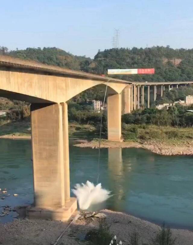 金沙江大桥一侧的金属制管道坠落至水中时，溅起数米高的水花。受访者供图