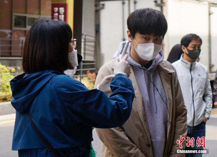 在韩国首尔一投票站，投票者接受体温检测。中新社记者曾鼐摄