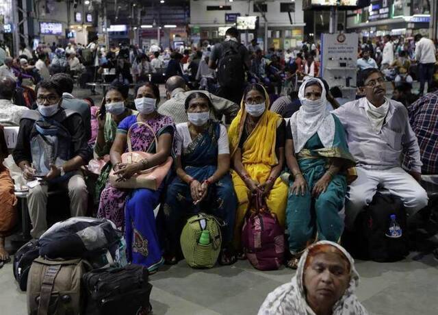 印度孟买，戴着口罩、正在等火车的乘客。图自美联社