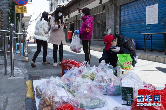 3月15日，湖北省襄阳市水星台社区党委书记刘晓琳（右二）和社区工作人员在查看、分发居民从网上订购的生活用品。新华社发（谢剑飞摄）