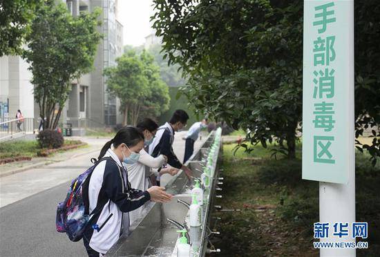 5月6日，武汉首批121所学校高三年级正式复学。在湖北省武昌实验中学，高三年级的学生入校后在手部消毒区洗手。新华社记者熊琦摄