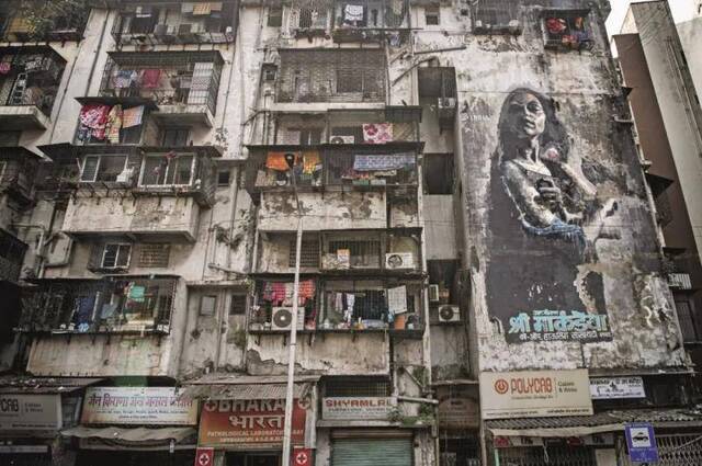 孟买街边的公寓楼，混凝土建筑已乌黑发霉，晦暗阴郁得像电影中的场景。