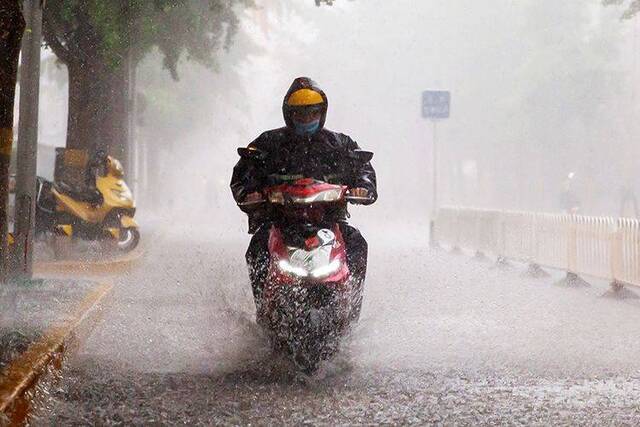 15时54分，海淀区文慧园路，行人骑车冒雨出行。