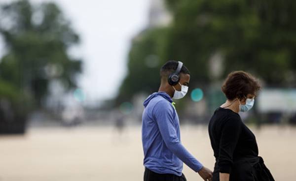 人们戴着口罩在美国首都华盛顿国家广场散步。新华社图