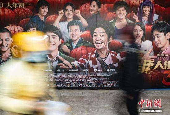 资料图：行人经过位于北京市朝阳区望京地区的一家电影院的户外广告。中新社记者侯宇摄