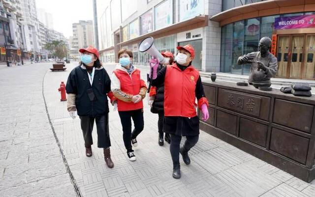 2月13日，武汉市汉正街石码社区党委书记兼居委会主任韩小琴（右一）带领社区工作人员向步行街旁的居民宣传防疫知识。新华社记者王毓国摄