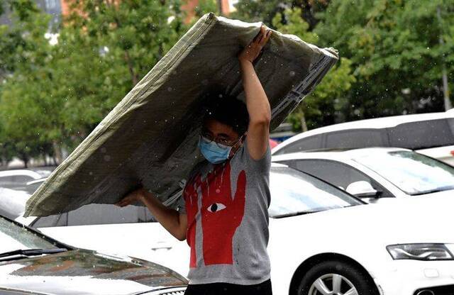 九龙山路，一名男子雨中搬运物品。