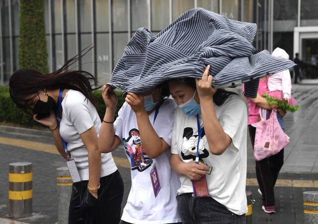 阵雨猝不及防，行人用外套遮雨。