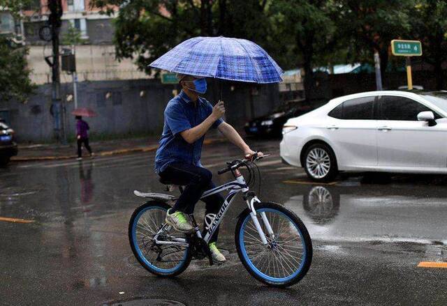 海淀区吴家场路，一名男子骑行在雨中。