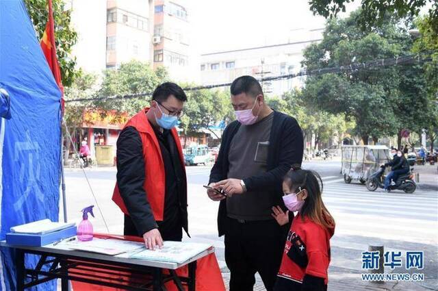 李文超（左一）在郑州市二七区兴华社区疫情防控卡点指导居民扫码登记（3月30日摄）。新华社记者郝源摄