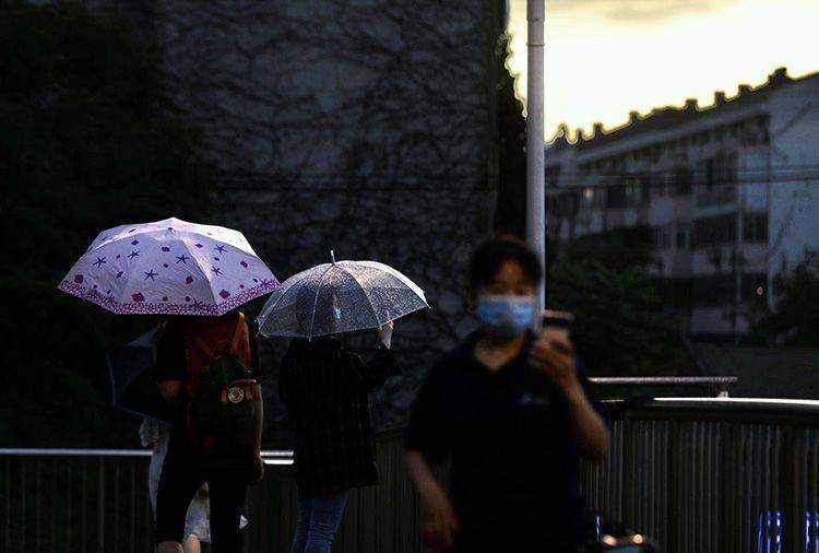 中关村东路过街天桥上，市民驻足拍摄雨景。