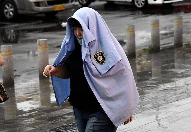 广渠路，公交乘务员把外套蒙在头上挡雨。