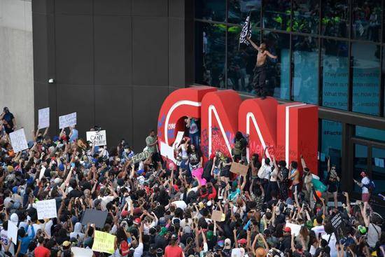 （图说：示威者在CNN总部外面的抗议游行中在徽标上绘画。图源/AP）