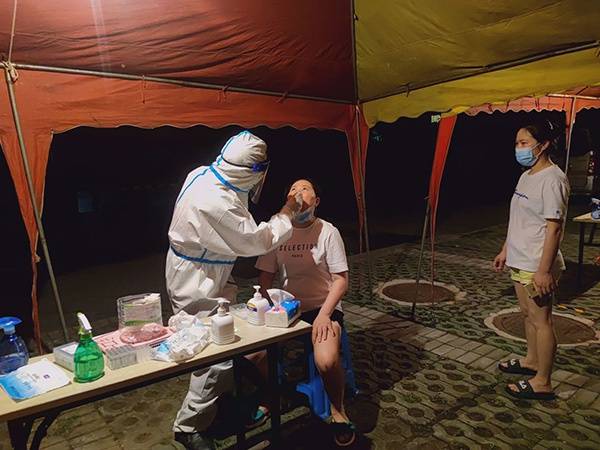 武汉市中医医院骨伤一科主任张汉庆在夜间为社区居民进行核酸采样。