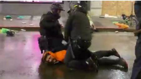 旁边一名警察把这名警察的腿用力拉到示威者背上