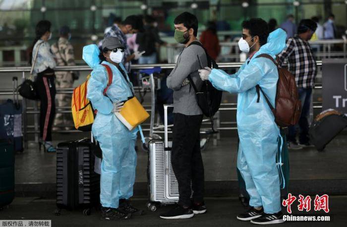  5月25日，在印度孟买希拉吉国际机场，旅客们穿戴着防护服和面罩出行。印度政府允许国内航线自5月25日起恢复。