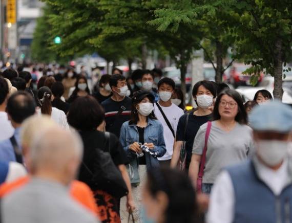 5月30日，行人戴口罩走过日本东京银座街头。当日是日本东京解除紧急状态后首个周六，各商圈人流量明显增多。新华社图
