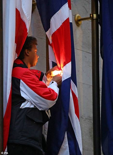 一名抗议者被拍摄到爬上国家战争纪念碑，并点燃了英国国旗。（图源：每日邮报）