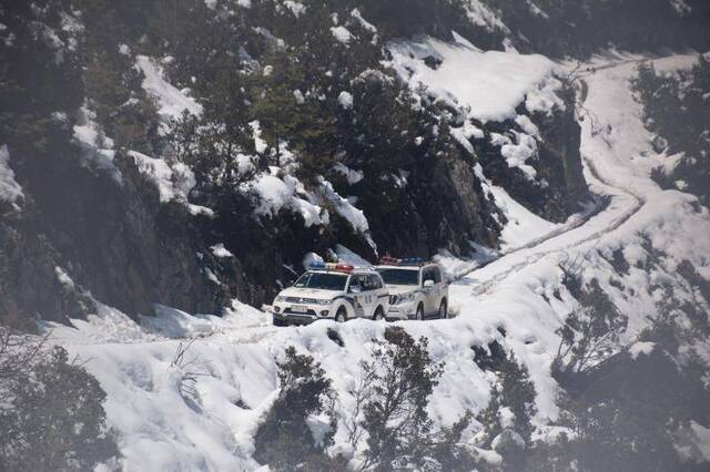 康定市公安局两辆巡逻车在冰雪山路上艰难前行