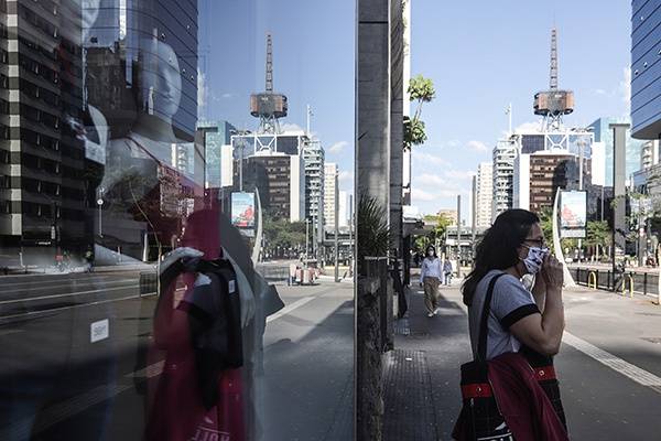 6月8日，一名女子在巴西圣保罗市一家关闭的店铺外调整口罩。本文图均为新华社图