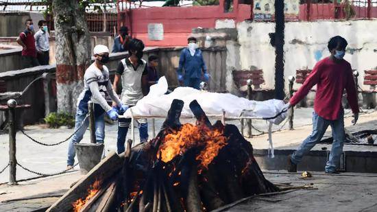 印度德里火葬场超载，新冠死者被露天架起柴火焚化