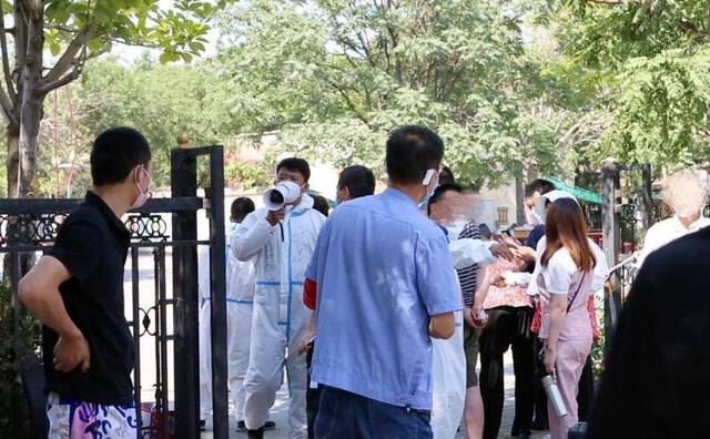  6月16日下午，卢沟桥街道青塔街心公园核酸检测点外，街道办工作人员在维持秩序。新京报见习记者赵敏摄