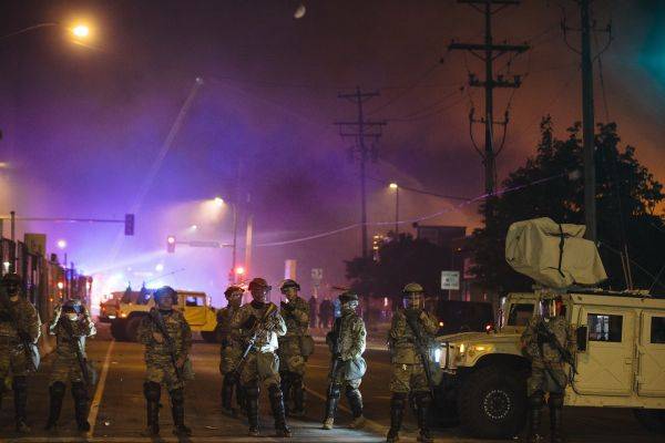5月30日，在美国明尼苏达州明尼阿波利斯市，国民警卫队成员在一处起火建筑附近警戒。新华社发