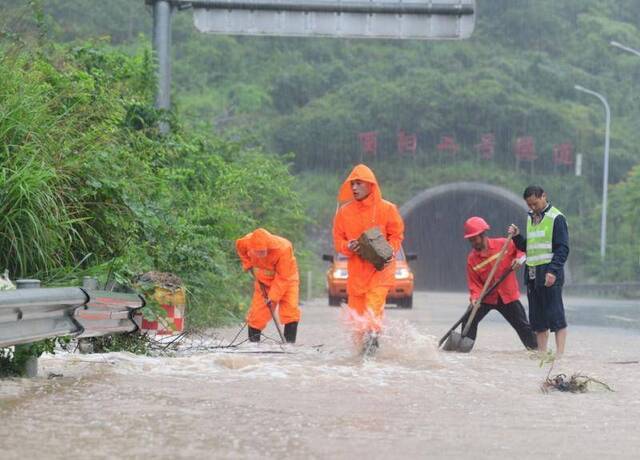 6月13日，在重庆市酉阳土家族苗族自治县境内酉沿高速公路上，工作人员在清理落石。新华社图