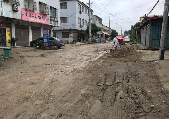 6月12日上午，因为刚下过大雨，一位八四集居民在填后街的泥泞路面。新京报记者肖隆平摄