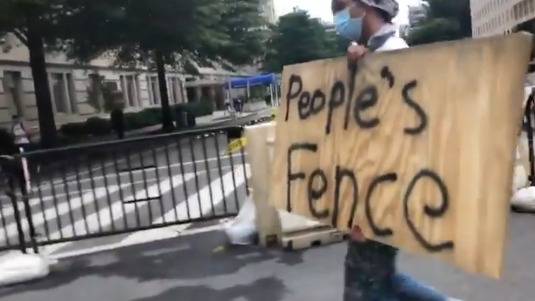 示威者举着写有“人民的围栏”的木板来源：视频截图