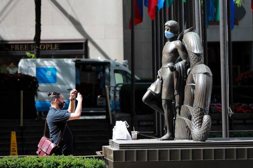 6月22日，在美国纽约洛克菲勒中心，一名男子拍摄“戴”口罩的雕像。新华社记者王迎摄