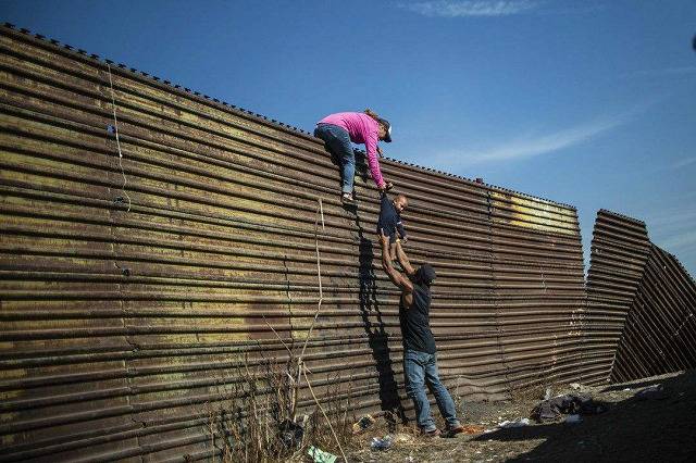 △美国和墨西哥边境的边境墙，非法移民试图翻越边境墙进入美国。